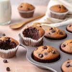 Chocolate cake mix muffins with chocolate chips in and around a muffin tin