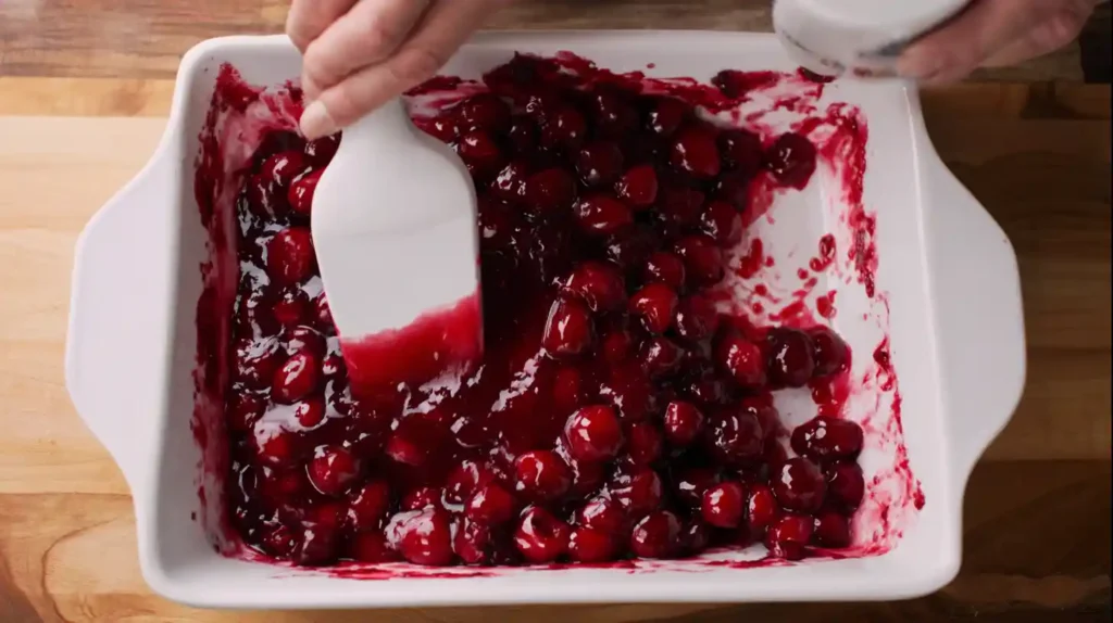 Pouring cherry pie filling into pan for Chocolate Dump Cake from Mix, a one-pan dessert recipe and easy desserts for families