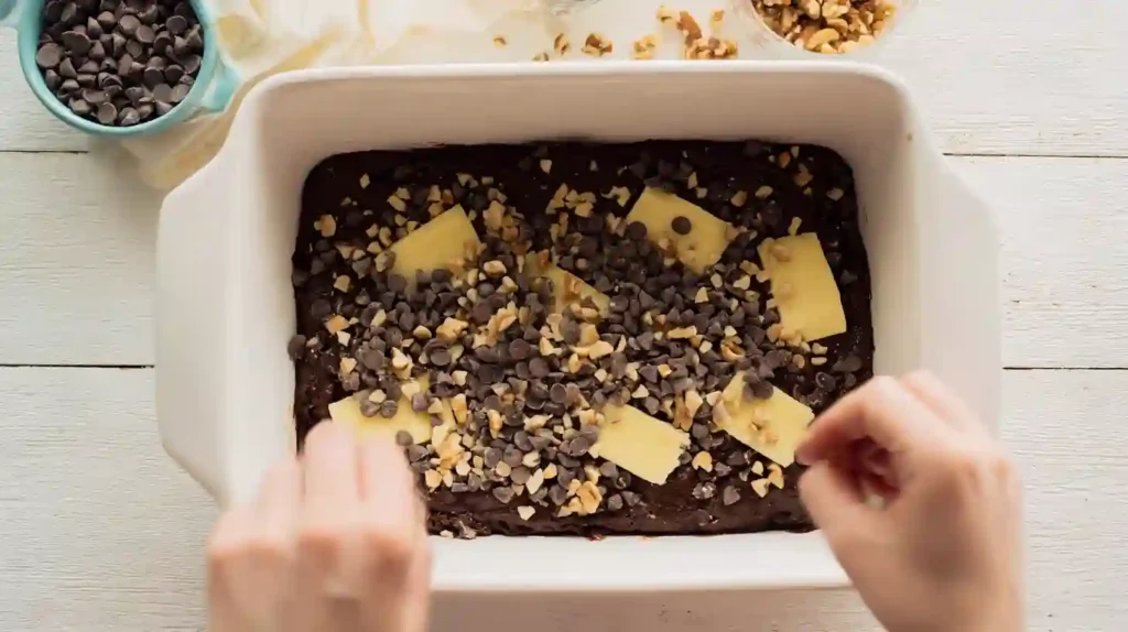 Sprinkling chocolate chips and nuts over Chocolate Dump Cake from Mix, one-pan dessert recipes and easy desserts for families using the best boxed cake mix recipes