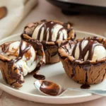 Chocolate cookie cups made in an air fryer filled with vanilla ice cream and hot fudge.air fryer chocolate cookie cups photo 1