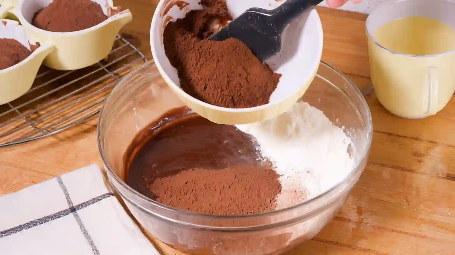 folding-cocoa-flour-air-fryer-chocolate-cupcakes Folding cocoa and flour into batter – easy chocolate dessert recipe using air fryer for busy families