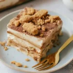 Slice of Biscoff lasagna on plate with crushed biscuit topping