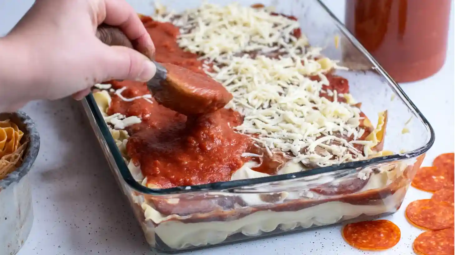 layering-pizzagna-bake-process Assembling pizzagna with layers of noodles and pizza toppings