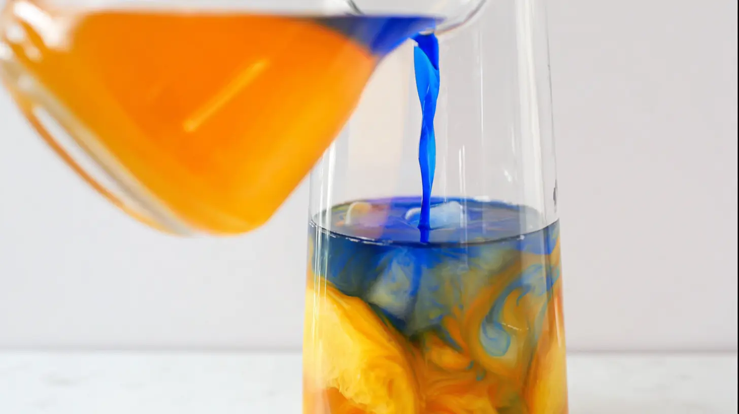 pouring-blue-curacao-punch Pouring blue curaçao into peach punch for swirl effect