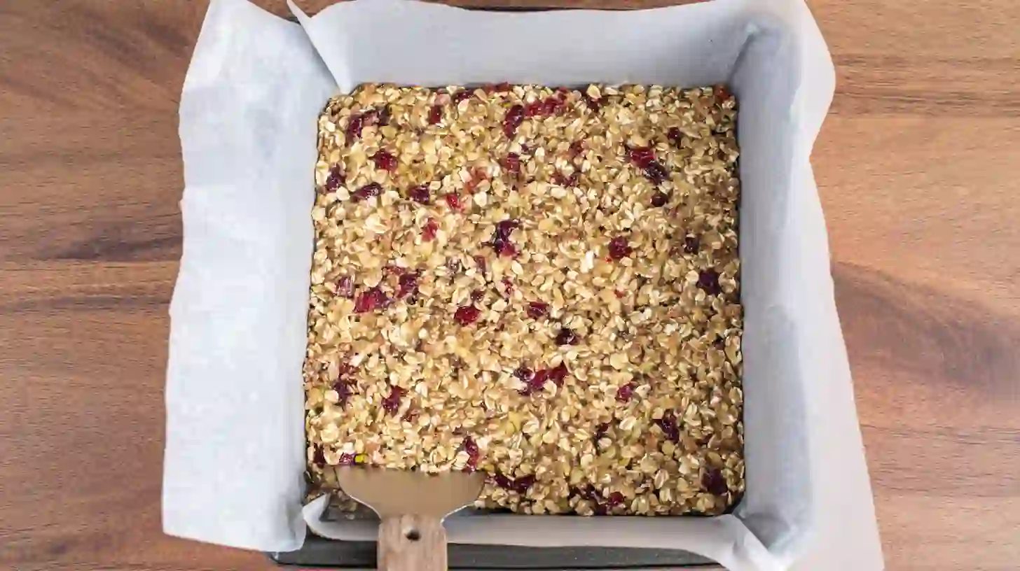 pressed-white-chocolate-cranberry-mixture forming oat mixture in pan before chilling