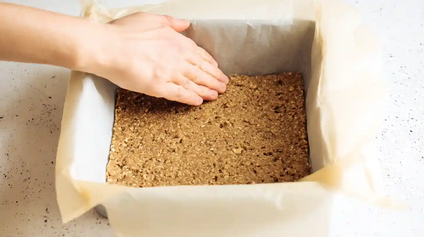 pressing-protein-bar-crust Pressing protein bar crust into a square pan