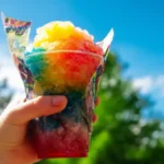 holding a rainbow Kool Aid snowcone Recipe outdoors