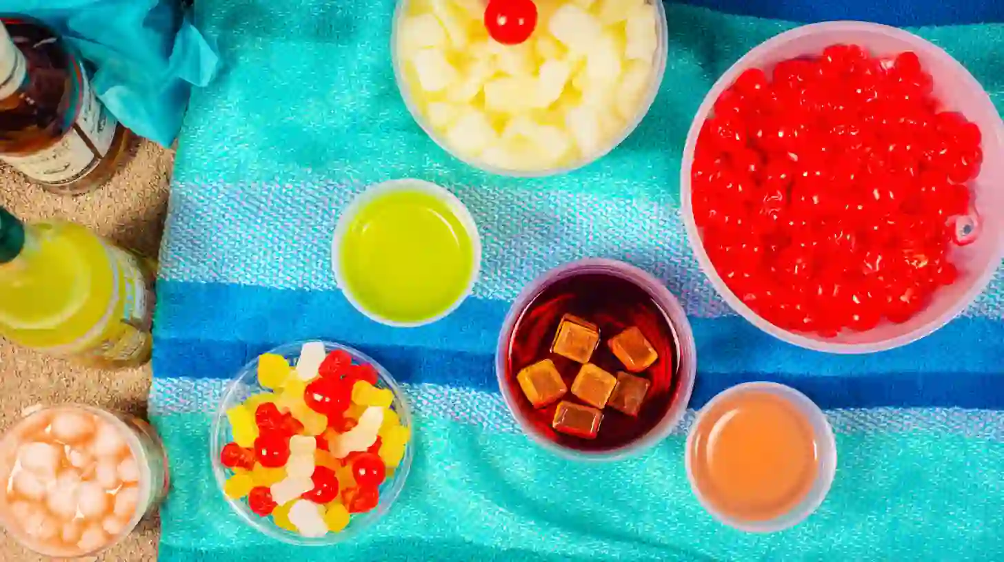 sunset-beach-bucket-Blast-ingredients Ingredients for Sunset Beach Bucket Blast arranged with tropical juices and candies