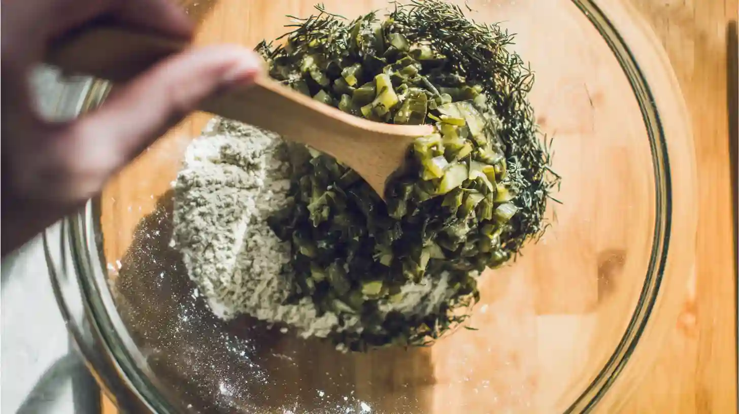 add-pickles-fresh-dill-bread Adding chopped dill pickles and fresh dill to bread mixture