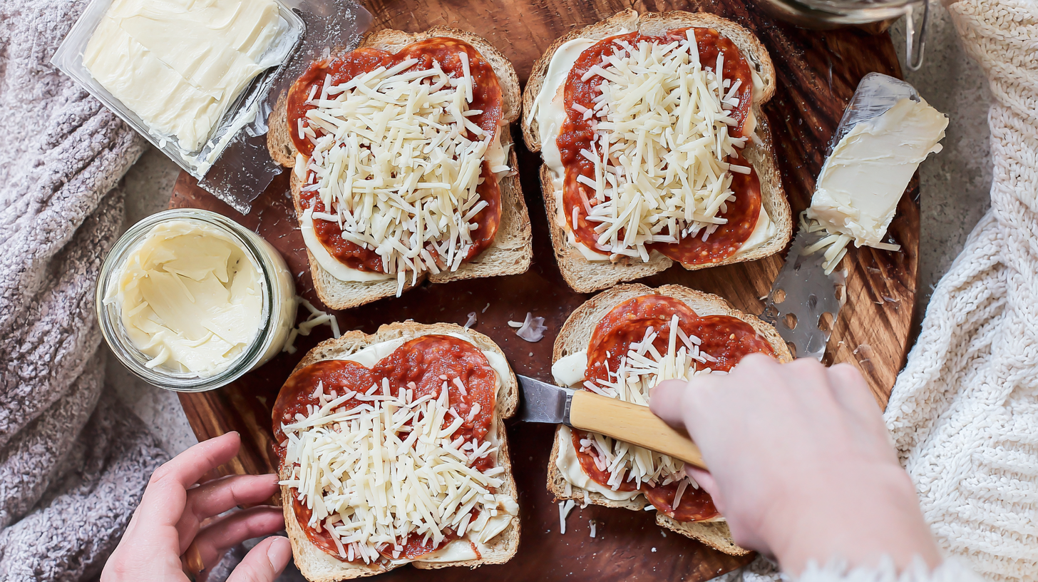 assemble-and-butter-pizza-grilled-cheese Assembling pizza grilled cheese sandwiches and spreading garlic butter on the outside