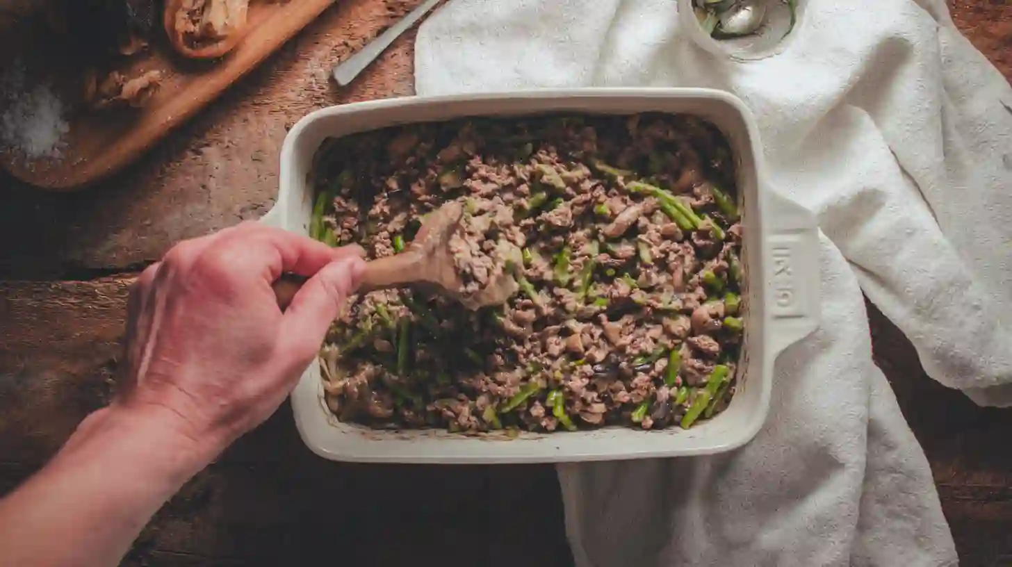 beef-mixture-into-casserole-dish-one-pan-dinner spooning beef mixture into casserole dish for easy one pan dinner