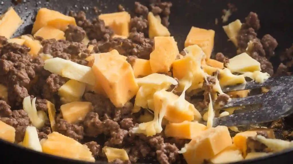 Melting cheddar and Parmesan into ground beef for creamy family dinner recipes and easy cheeseburger appetizer ideas