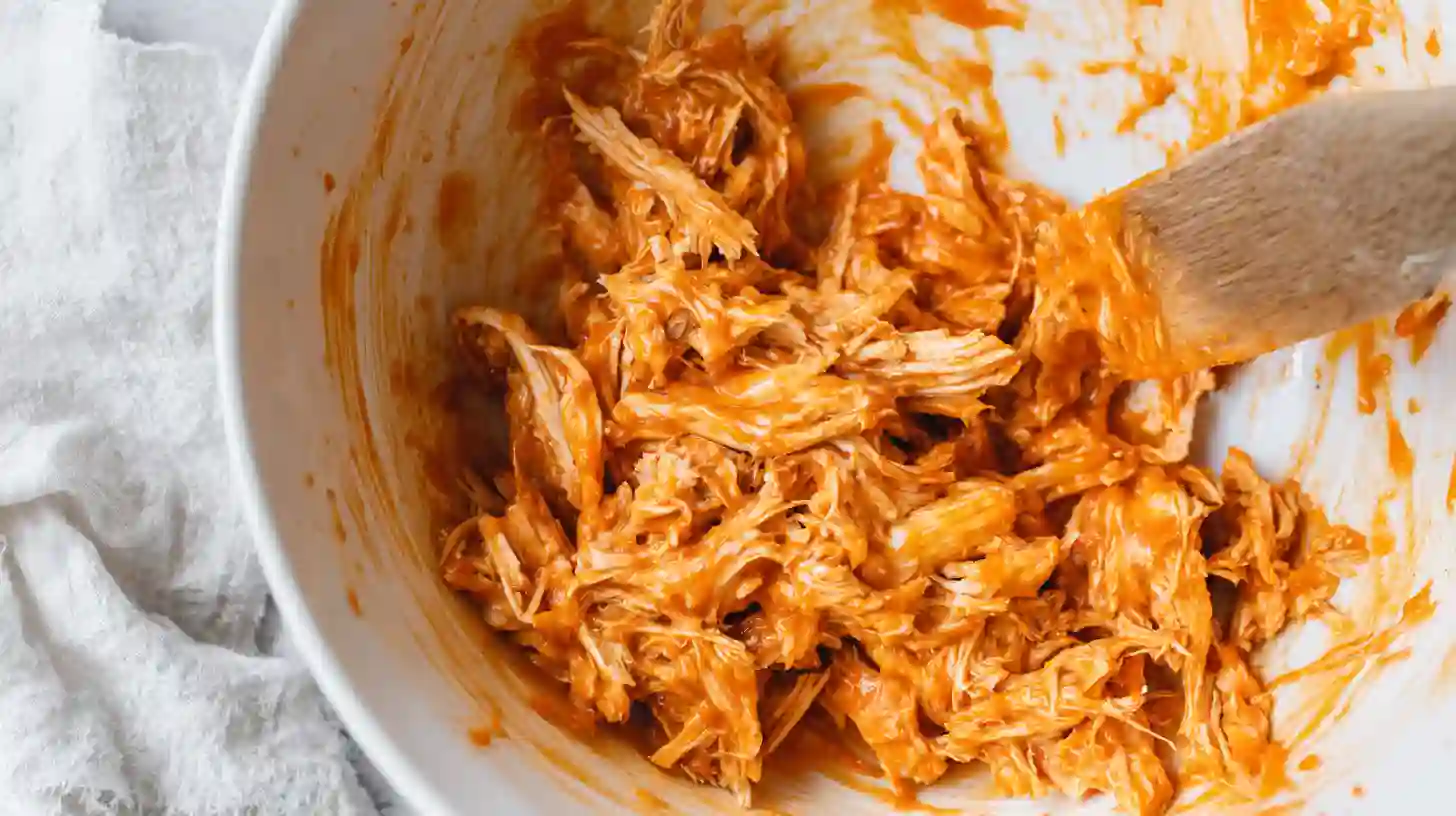 mix-buffalo-sauce-chicken-step2 Tossing shredded chicken with buffalo sauce in mixing bowl