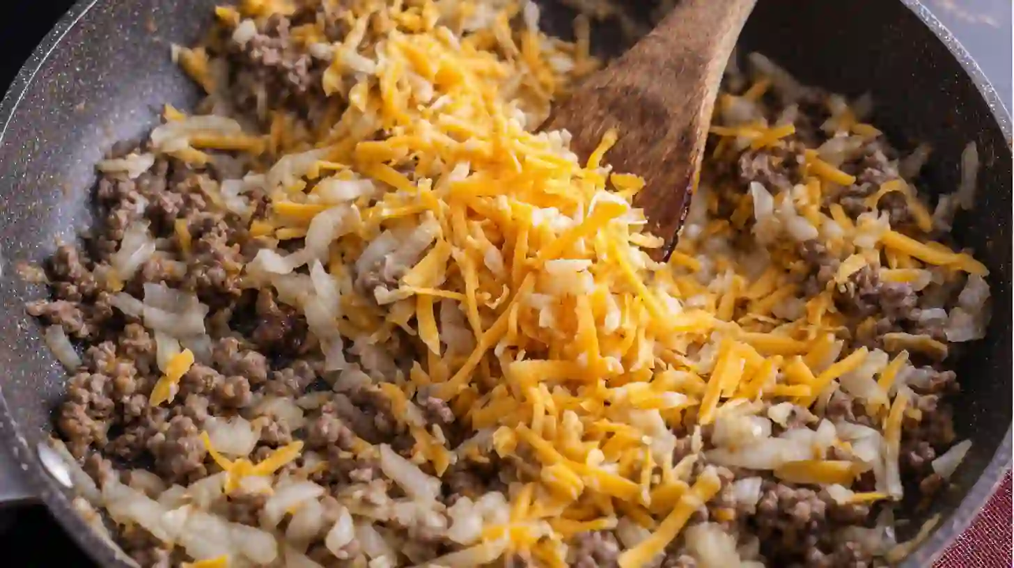 mix-cheddar-beef-rollups Mixing shredded cheddar into cooled beef filling