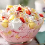 individual cup of pink lemonade fluff salad topped with coconut and strawberry.kid-friendly party dessert recipes