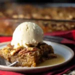 Warm slice of easy pecan pie dump cake with vanilla ice cream for best cake recipes for bake sale