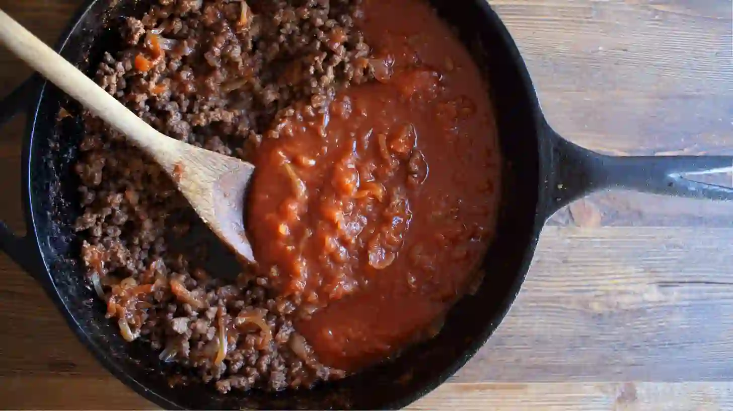 sloppy-joe-potato-skillet-simmer-sauce Simmering Sloppy Joe sauce with ketchup, mustard, and BBQ in skillet – high-protein ground beef skillet meal for easy family dinners