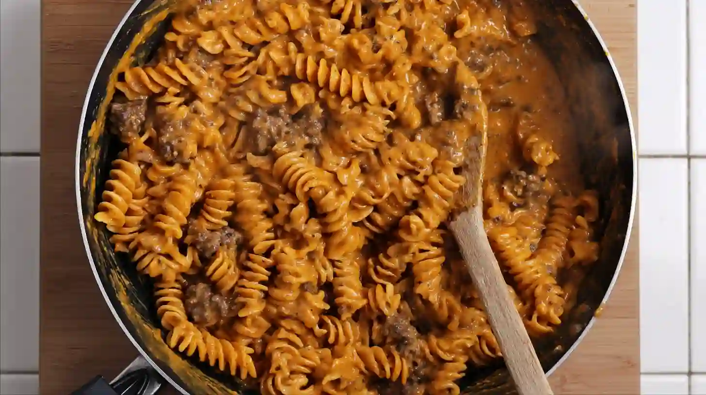 toss-rotini-creamy-cajun-beef-skillet steep5 Tossing rotini into creamy Cajun garlic beef sauce for high-protein pasta skillet