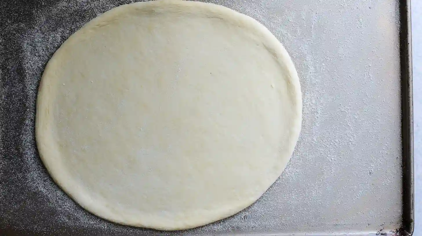 best-roasted-garlic-white-chicken-pizza-step1-dough-base Best roasted garlic white chicken pizza dough rolled into 12-inch base on cornmeal-dusted baking sheet – easy homemade Italian recipe preparation.