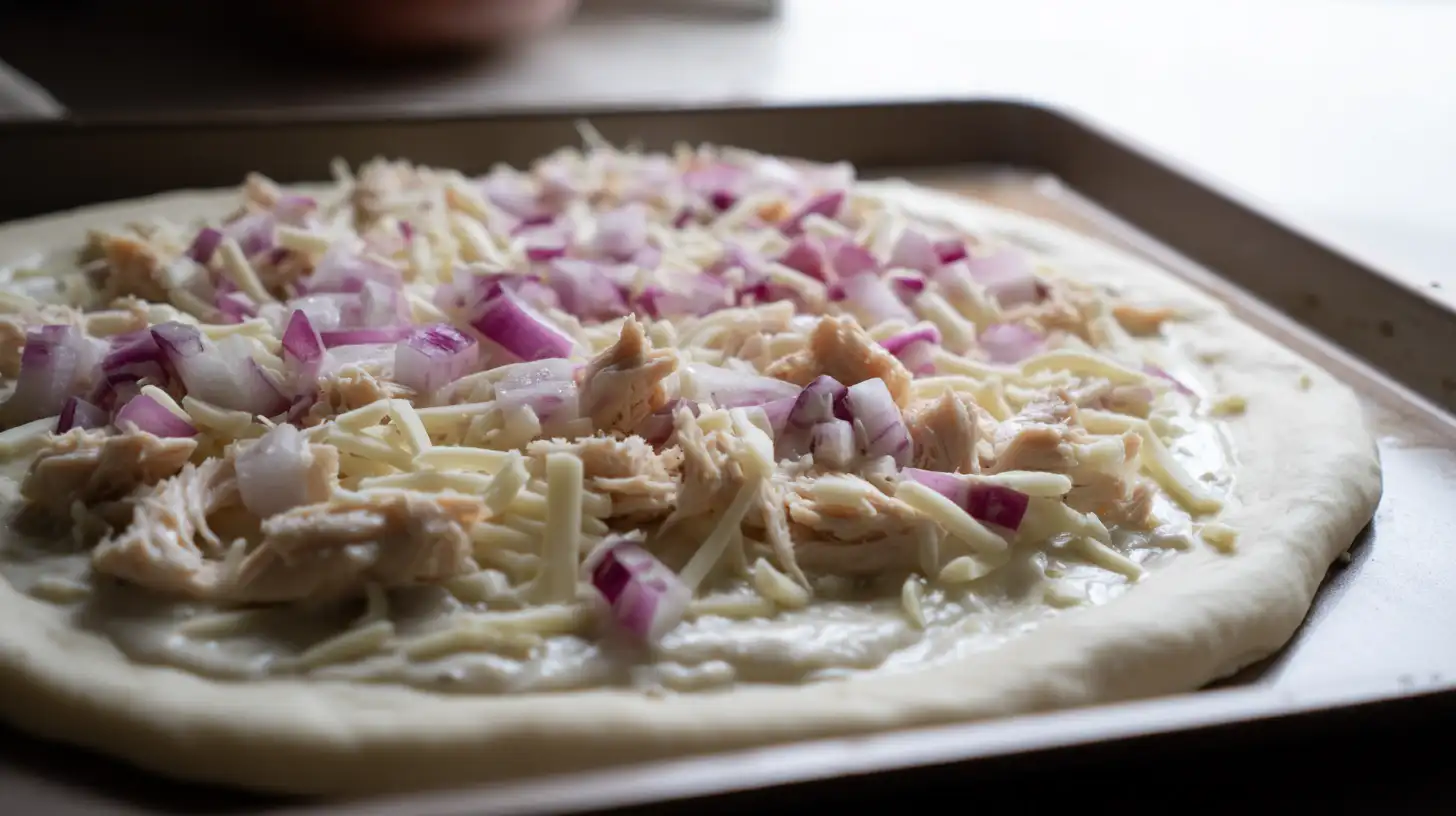best-roasted-garlic-white-chicken-pizza-step3-layer-toppings Best roasted garlic white chicken pizza layered with creamy sauce, shredded chicken, mozzarella, and red onion – easy homemade Italian recipe preparation.
