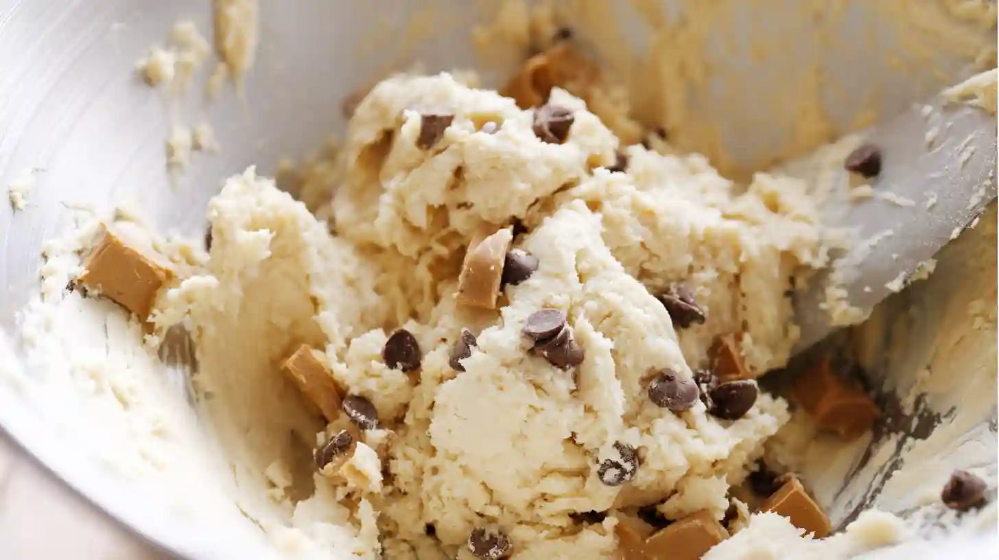 mixing-dough-dairy-milk-caramel-cookie-cups Folding flour, baking soda, salt, Dairy Milk Caramel pieces, and chocolate chips into cookie dough – perfect for caramel cookie cups