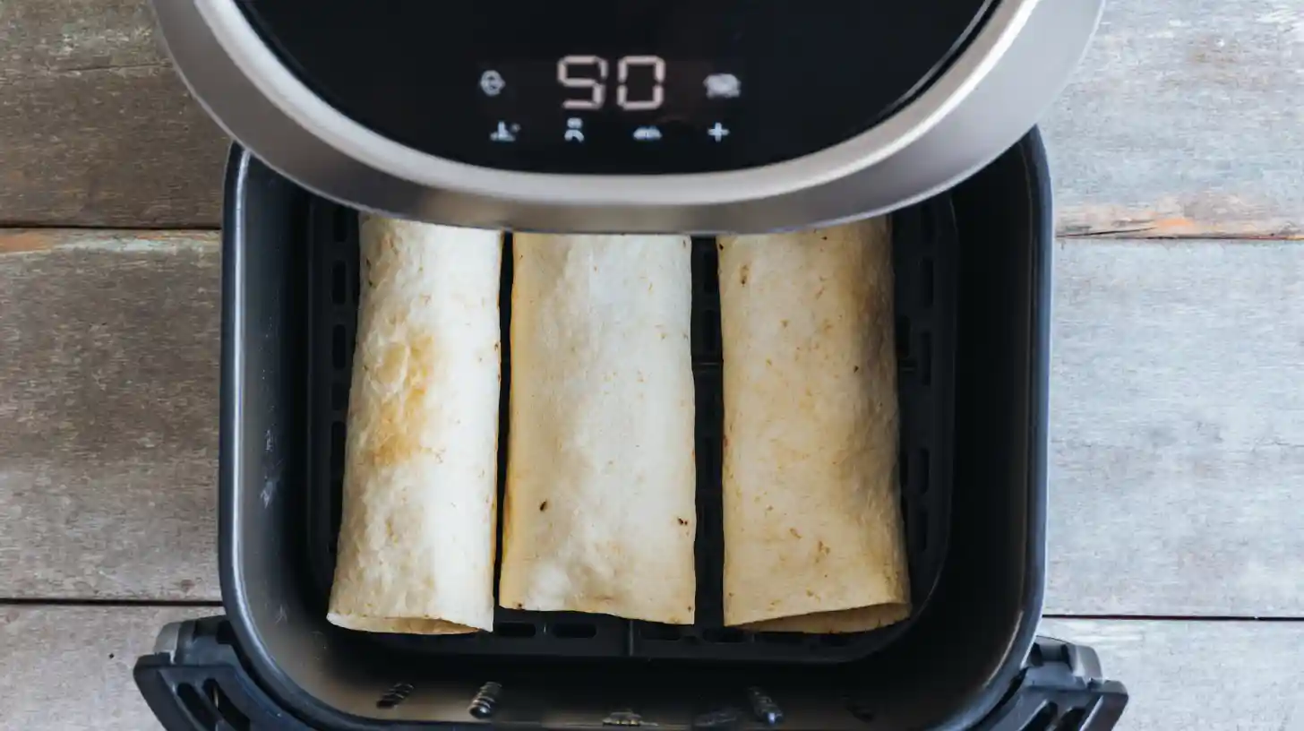 air-fryer-chicken-ham-and-cheese-wraps-step5-airfry Step 5 Air Fryer Chicken Ham and Cheese Wraps – seam-side down in air fryer, crispy chicken wrap air fryer recipe, quick air fryer recipes for busy moms.