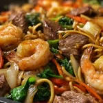 Steak and shrimp stir-fried noodles in savory sauce with vegetables.meal prep ideas with steak and shrimp