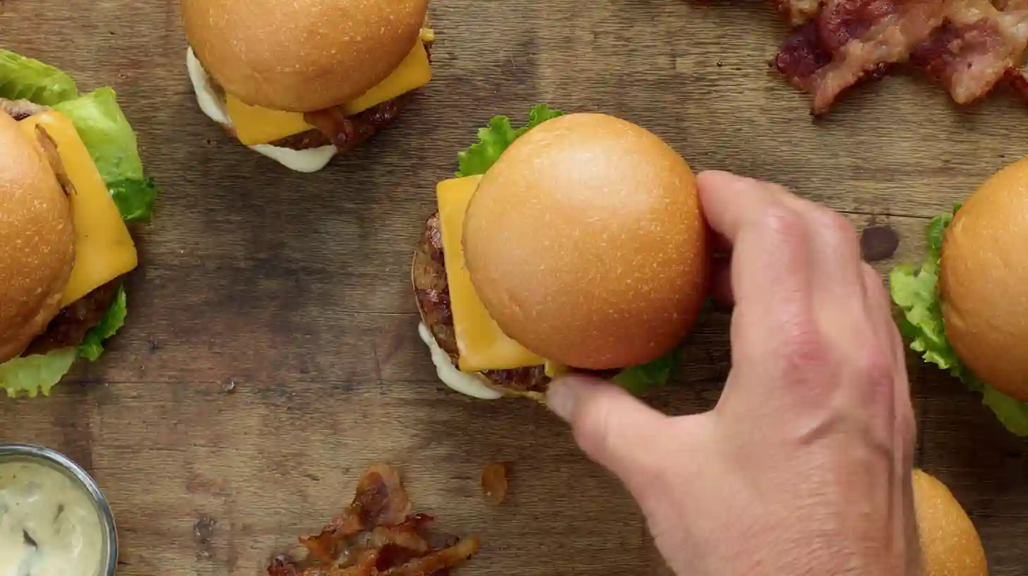 step4-toast-layer-pork-cider-sliders Toasting slider buns and layering pork patty, cheddar, and lettuce for Harvest Apple Cider Pork Burger Sliders – easy dinner recipes for families.