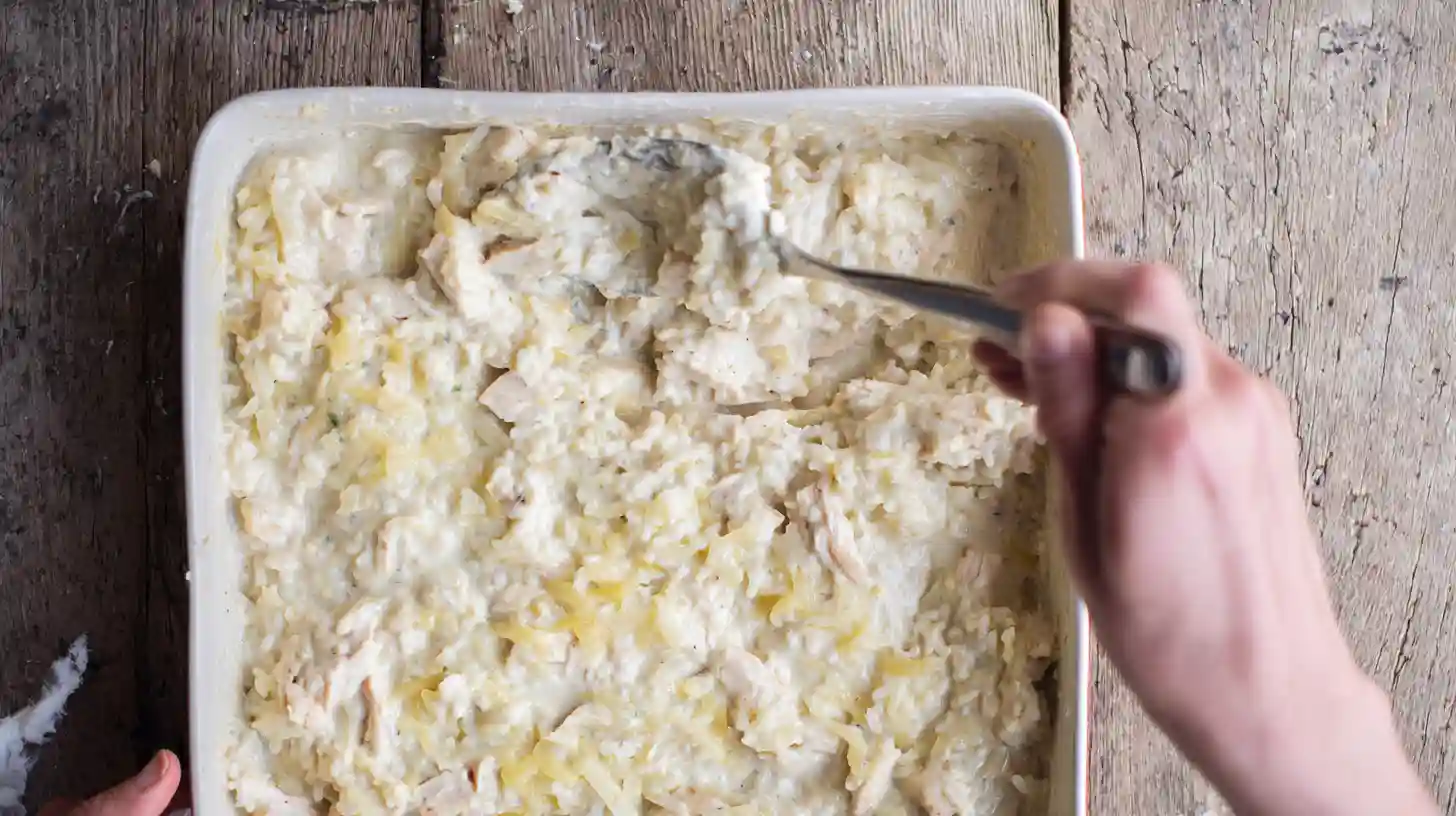 step2-french-onion-chicken-rice-bake-pan-prep Spreading creamy French onion chicken and rice casserole into baking dish for an easy chicken casserole recipe