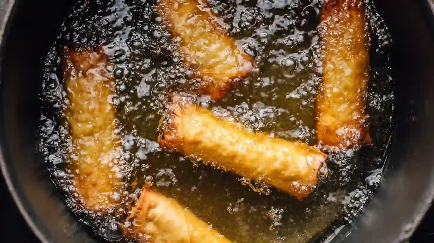 Texas Twinkies egg rolls frying in bubbling peanut oil — golden and blistered brisket-stuffed appetizers for game day or party snacks