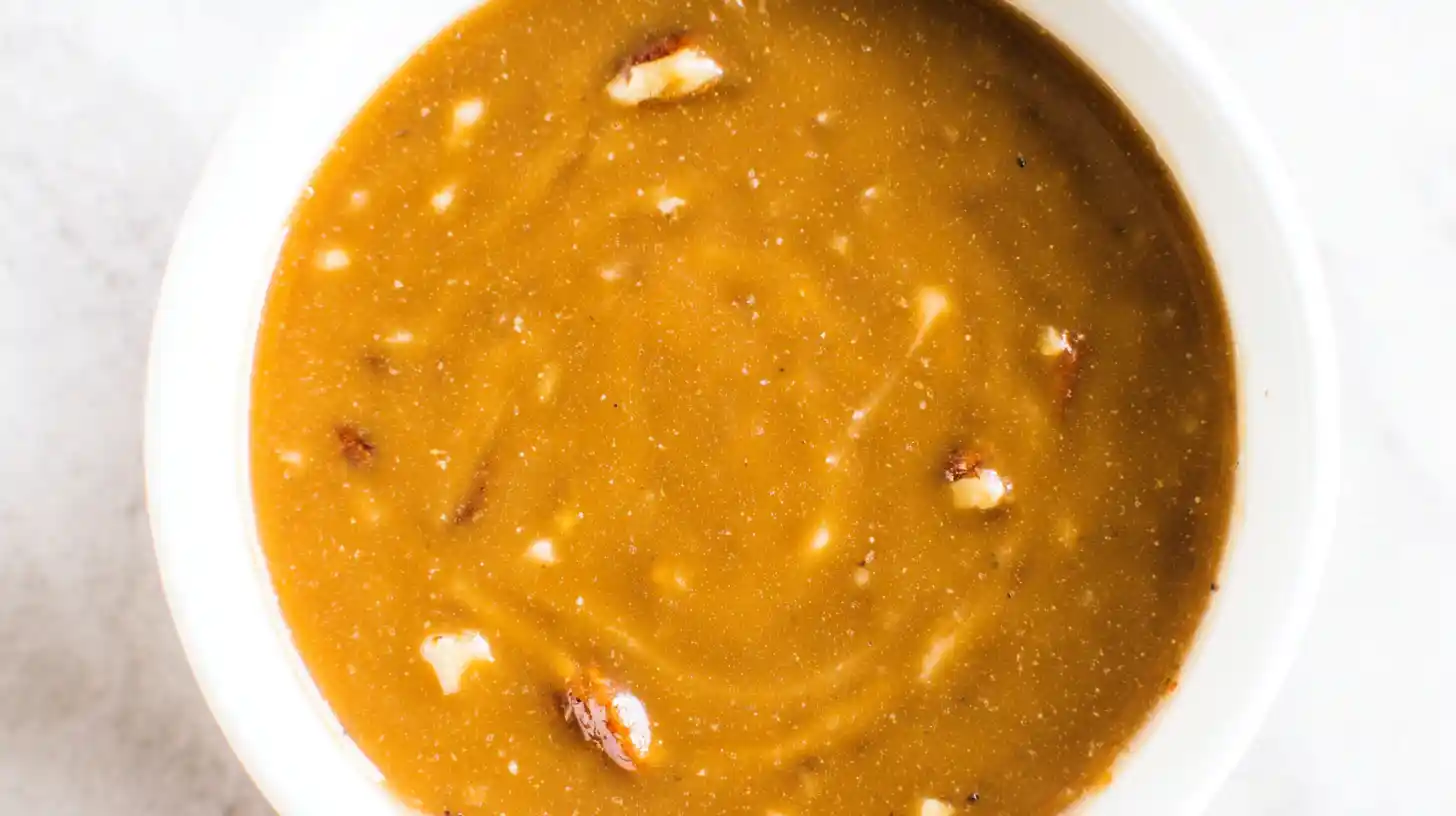 Maple pecan dessert sauce in a white bowl with visible chopped pecans — easy maple syrup glaze recipe for cookies, pancakes, and fall desserts