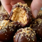 Close-up of No-Bake Peanut Butter Cheesecake Balls coated in chocolate and topped with crushed peanuts