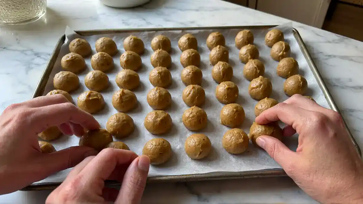 Shaping peanut butter cookie dough into 1-inch balls on parchment paper — easy small batch kid-friendly cookie recipe